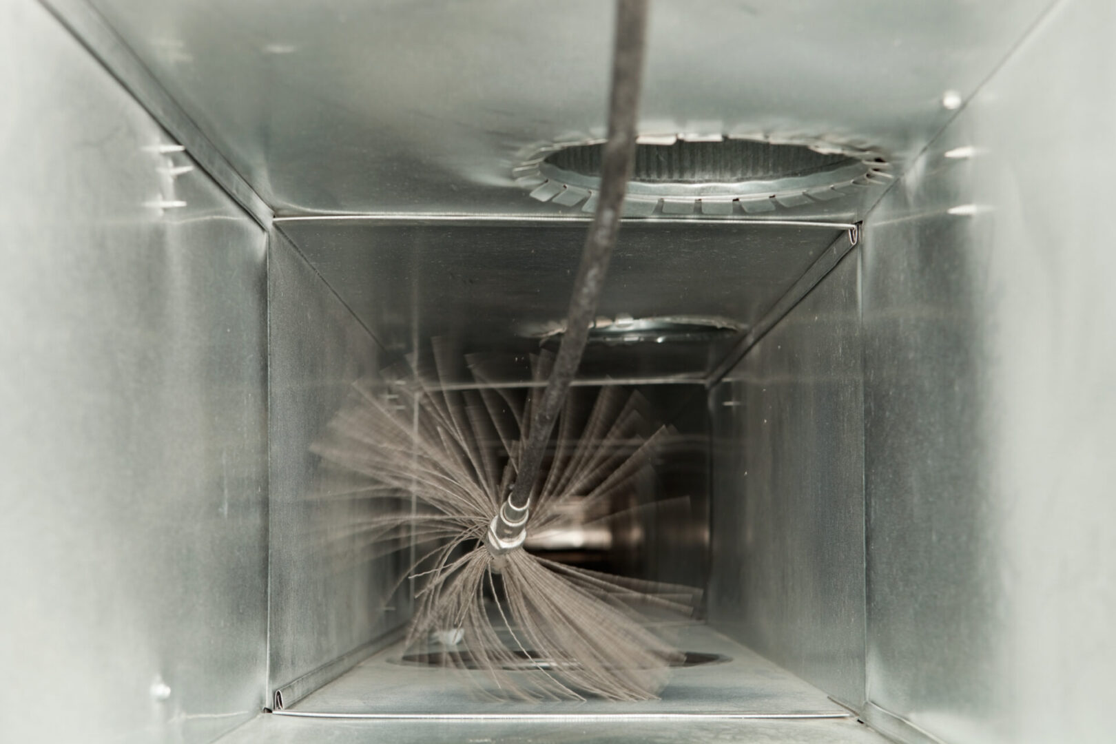 Cleaning brush inside metal air duct.