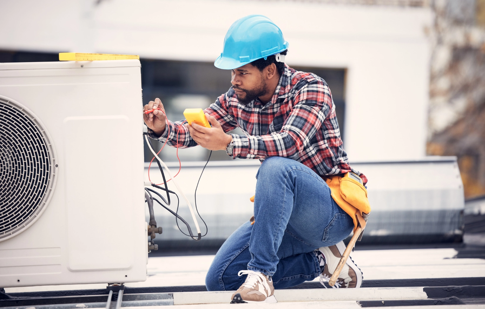 Man in a hard hat sitting on the roof of a building, holding a mobile phone