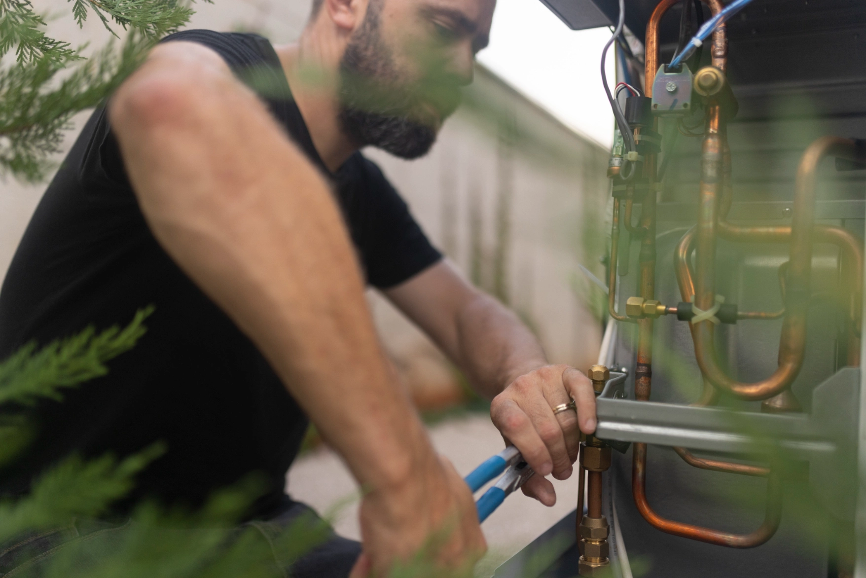 Man working on a water heater, holding a tool in his hand