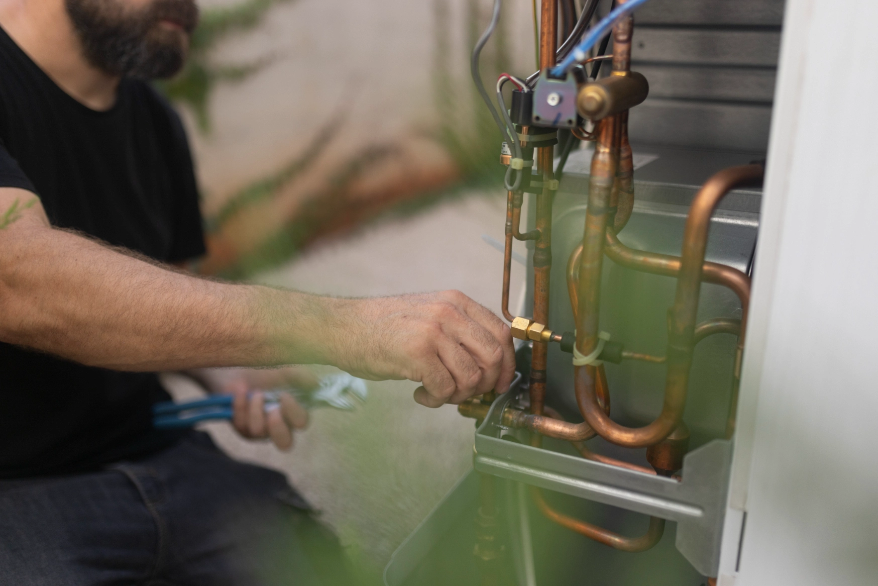Man working on a gas furnace, holding a tool in his hand